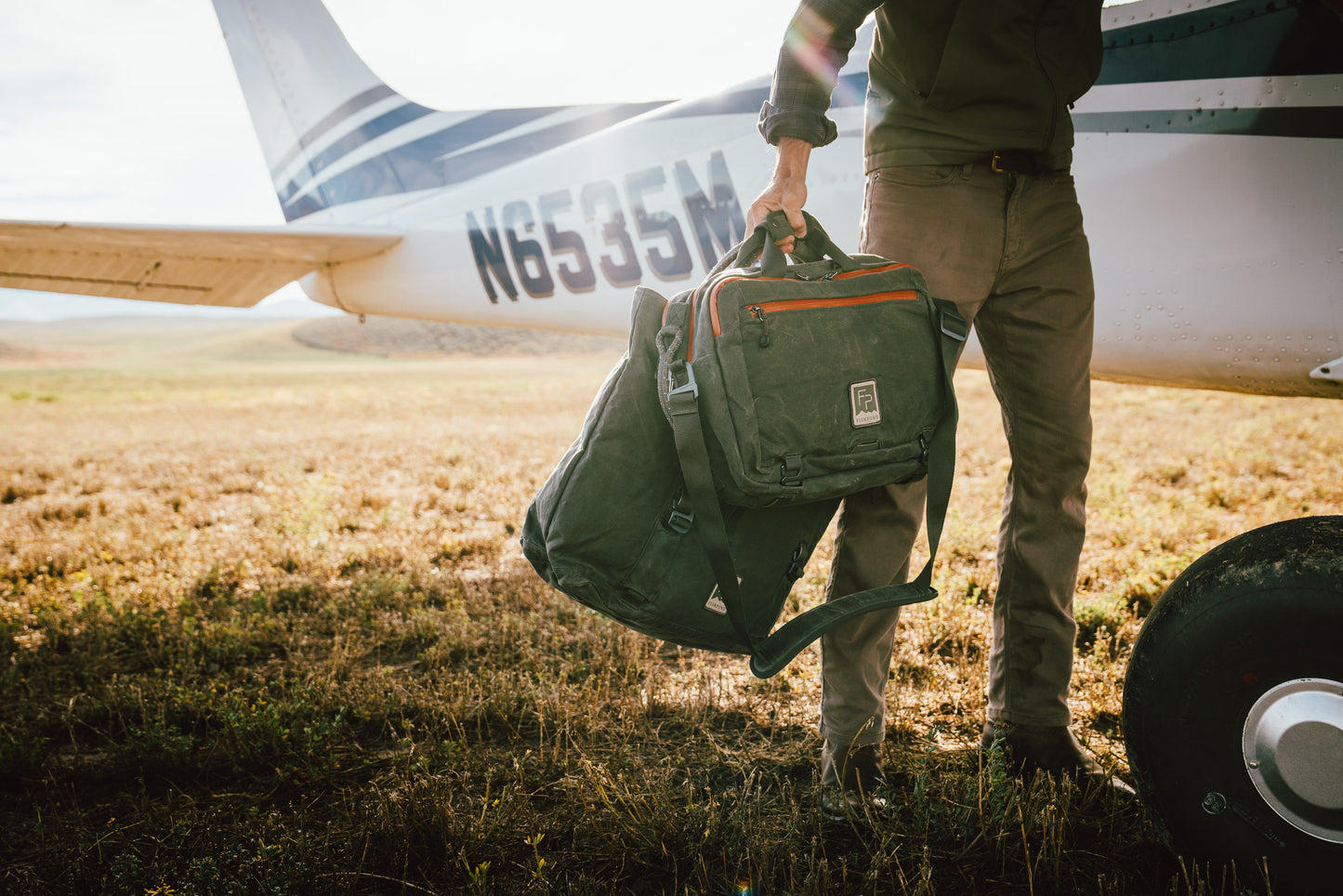 FP Field bags near a small airplane in a grassy field